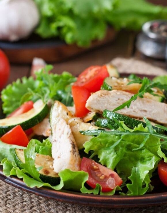 A plate of greens, veggies and chicken strips