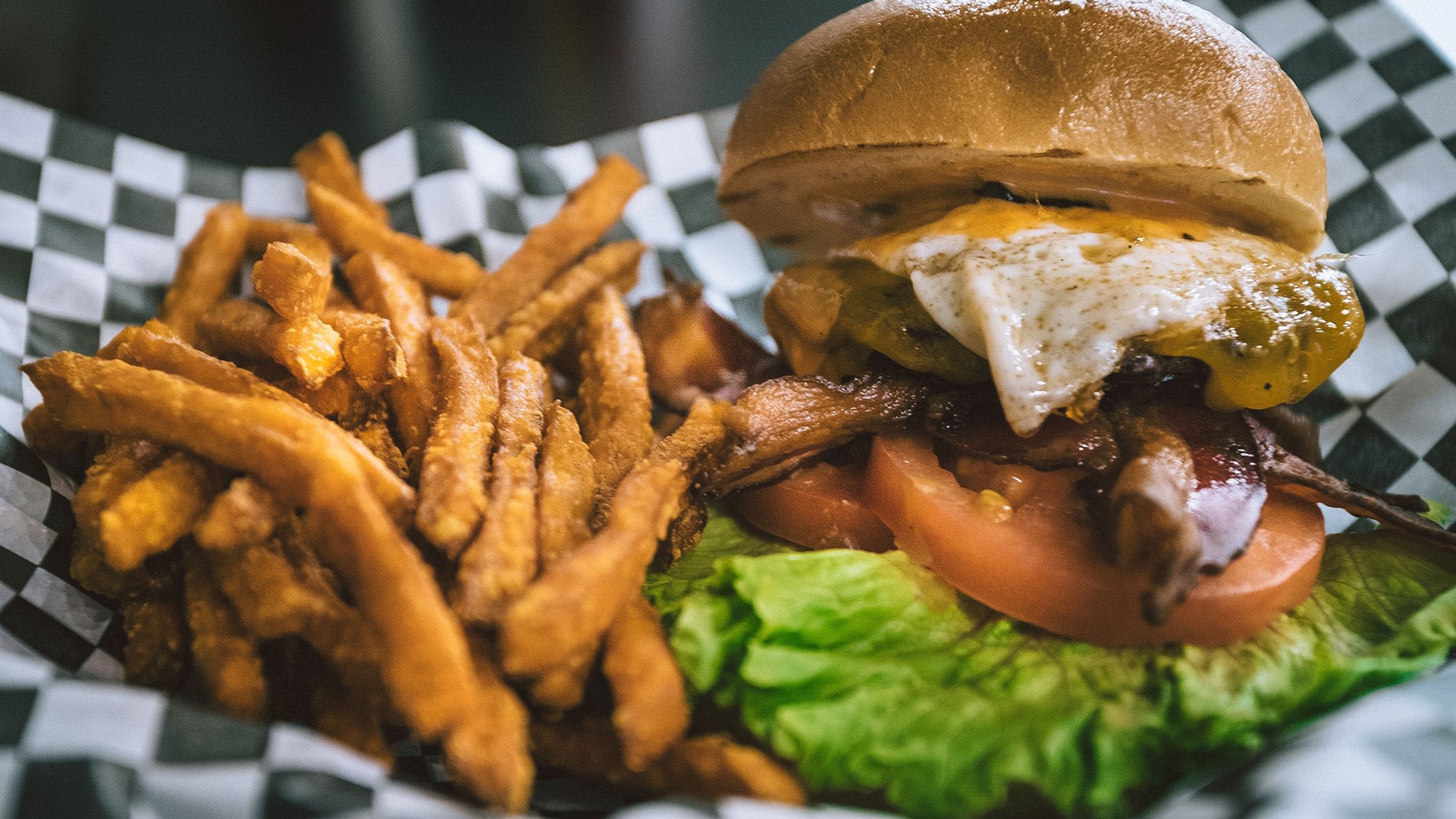 A greasy burger with fried egg and a side of fries