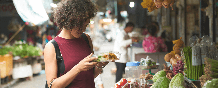 Woman carefully examining a container of food from a street market