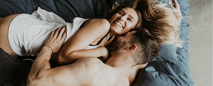 Young couple laying in bed laughing