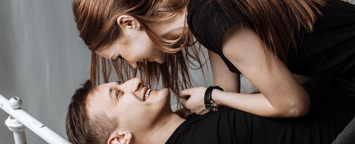 woman on top of man smiling about sexual positions for back pain