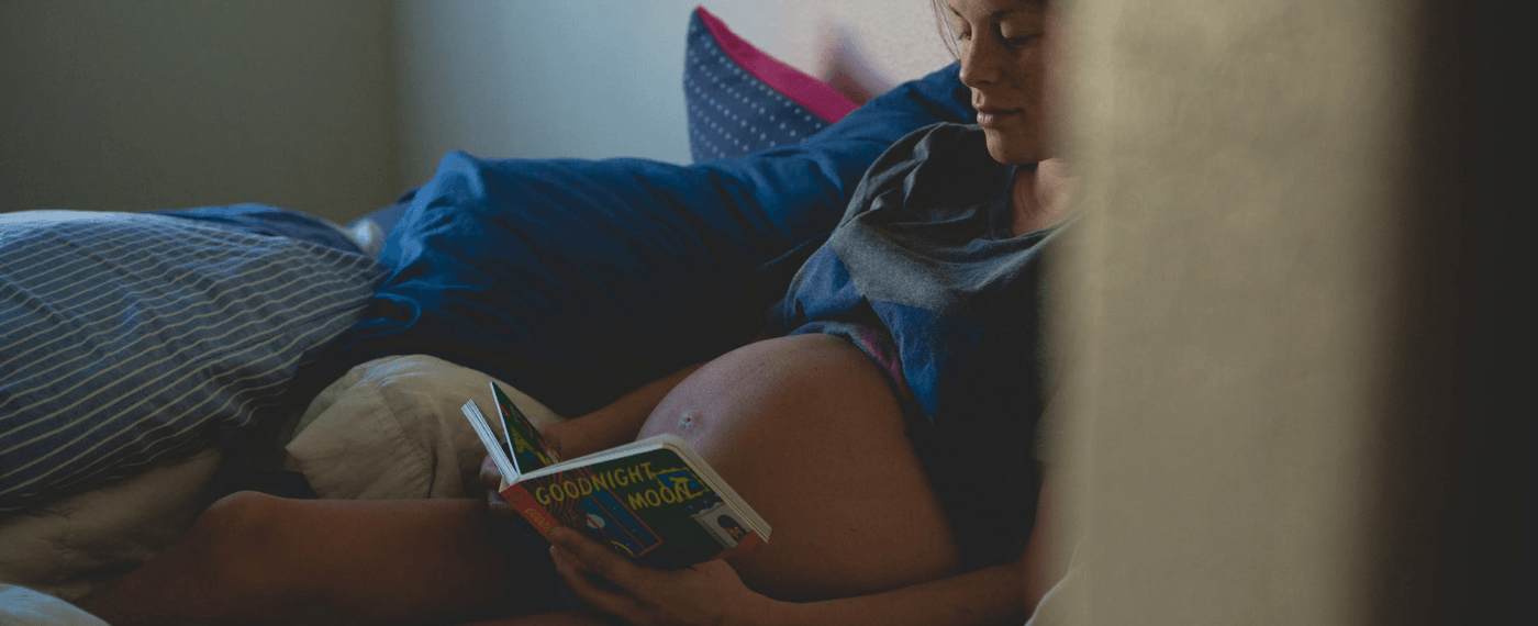 expecting mother reading book about the do's and don't during pregnancy