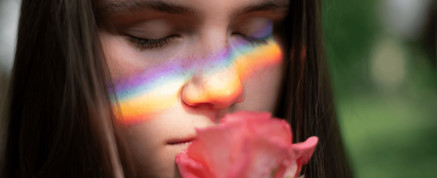 a girl smiling a rose with a light prism across her face