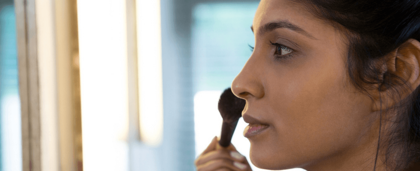 Woman applying blush to her face with makeup brush