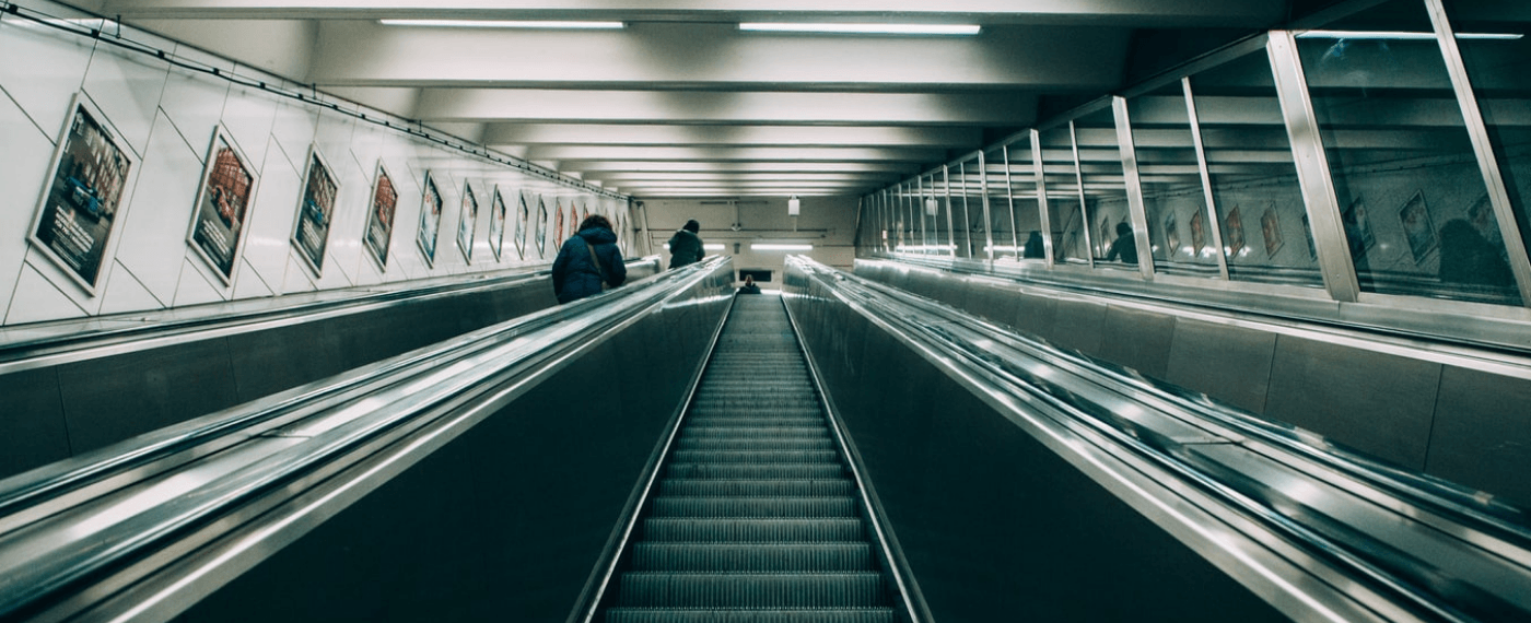 an image of a subway escalator stairs where the fluorescent lights causes headaches