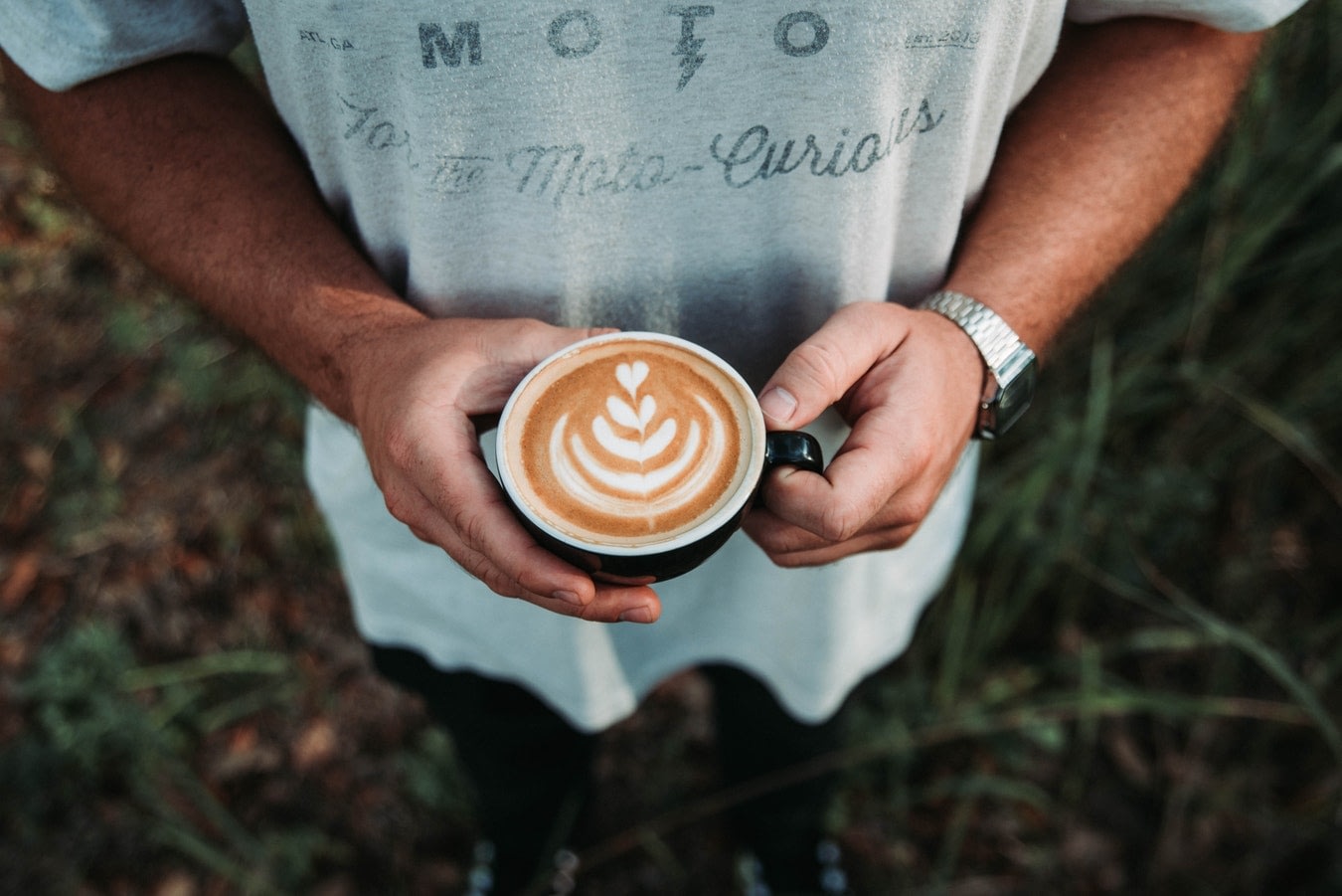 A man holding a cup of cbd coffee with heart shaped foam
