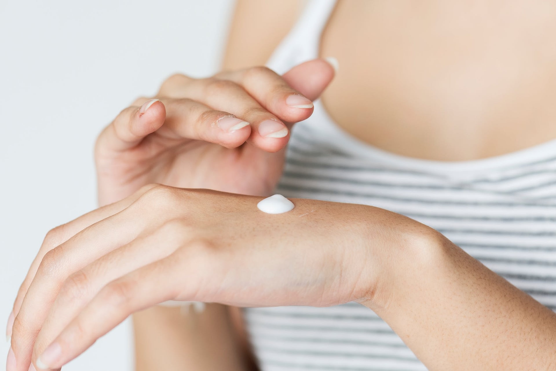 a woman using hand lotion to moisturize