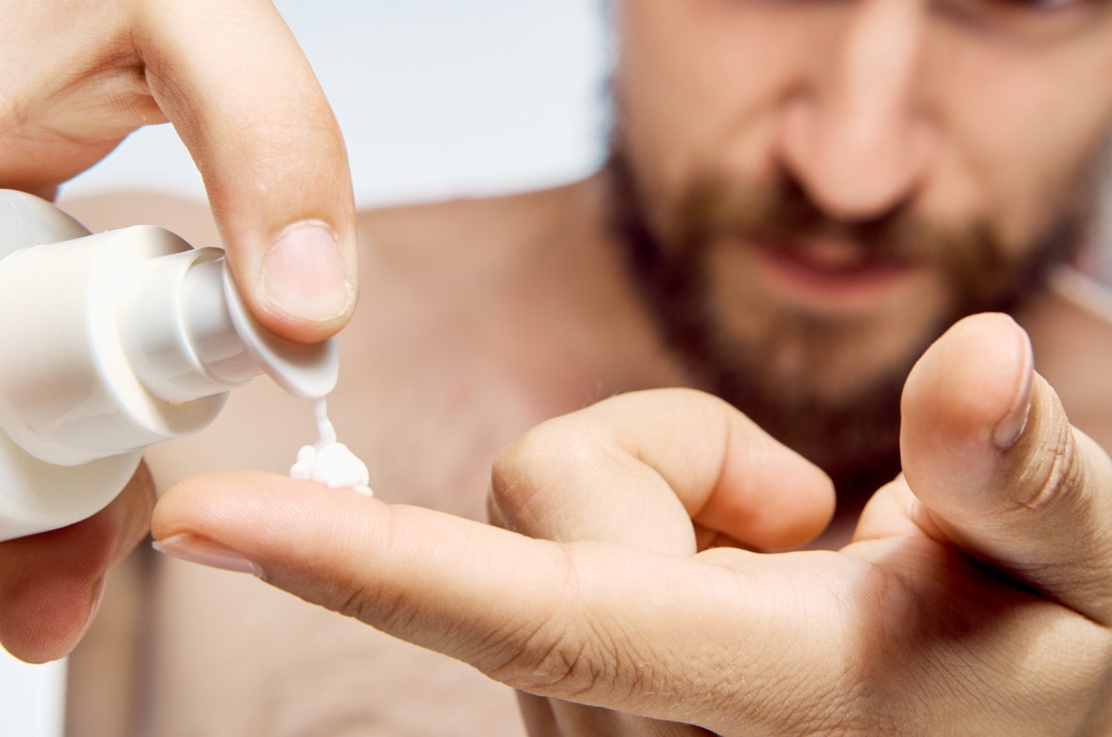 man placing a drop of skin care lotion on his finger tip