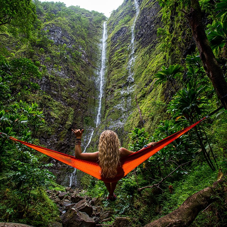 Woman relaxing in a hammock overlooking a waterfall in a rain forest