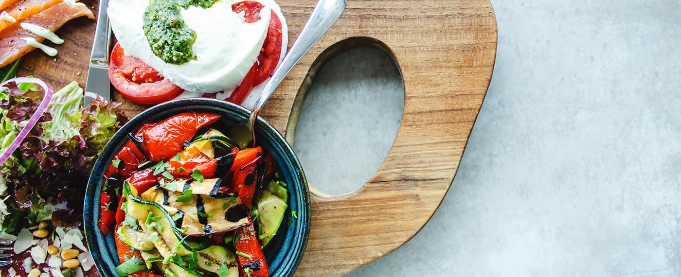 Bowl of grilled peppers and vegetables with mozzarella and tomato caprese on the side