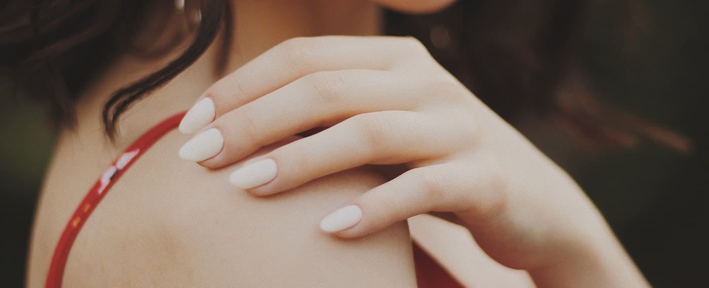 Young woman modeling her nails with hand on shoulder
