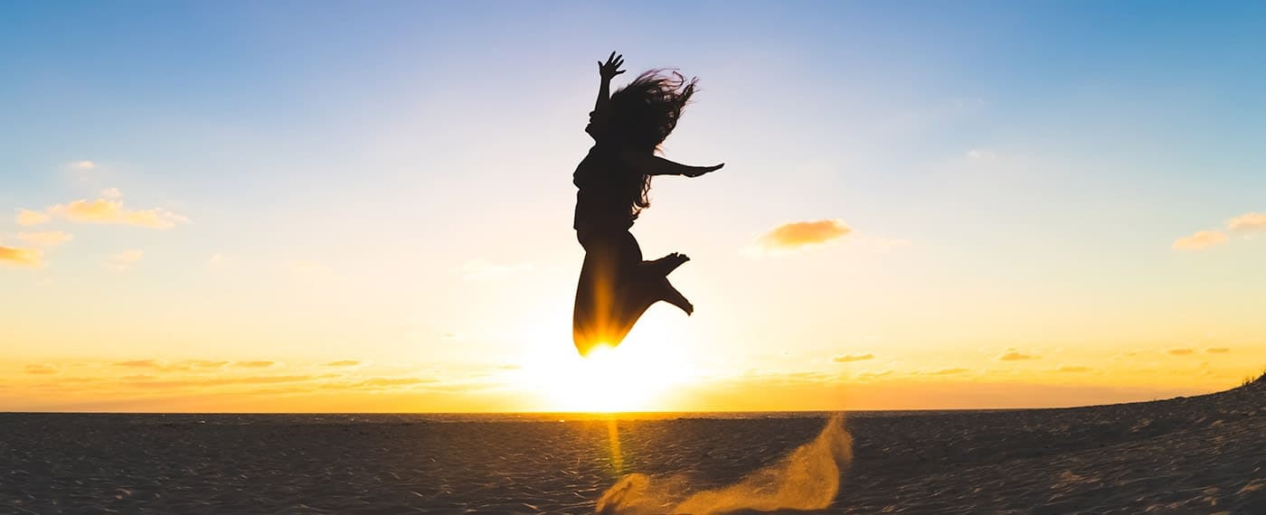Woman jumping into the air with the sunset in the background