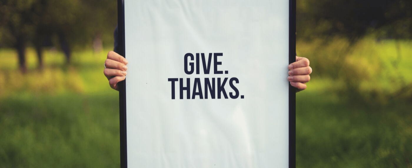 A sign being held up that reads "Give. Thanks."