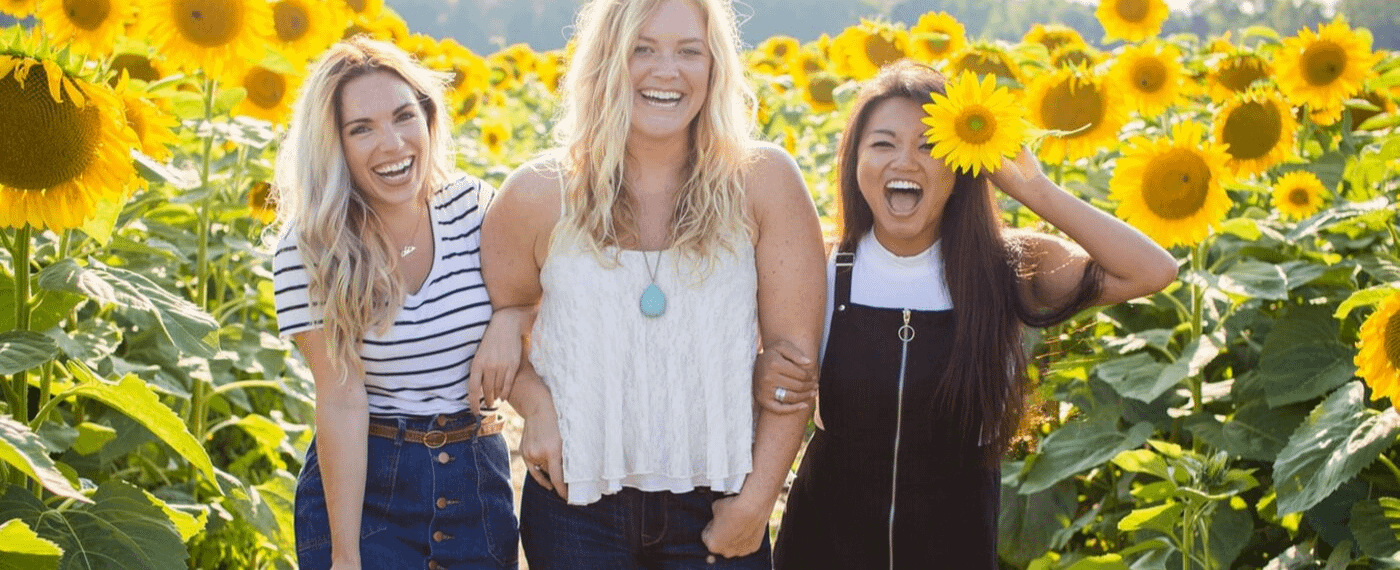 Young women with different body types standing in a field of sunflowers