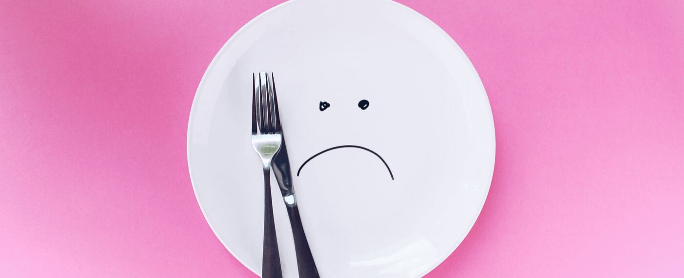 An empty plate with sad face drawn in the center