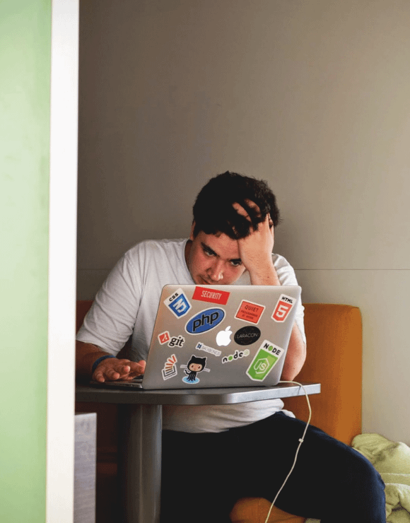 Stressed male looking upset at laptop screen
