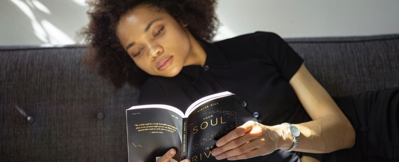 Woman leans over reading a book about being kind to yourself