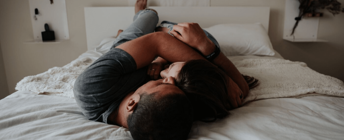 Man and woman cuddling each other while lying in bed