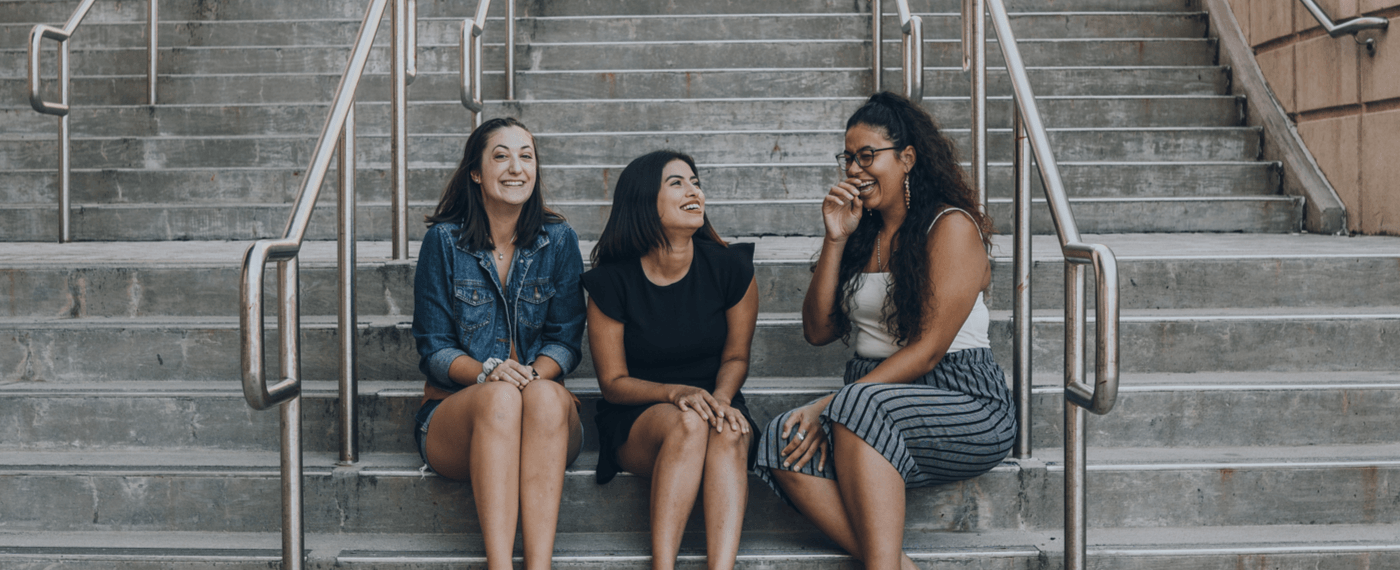 Three women sitting on steps laughing
