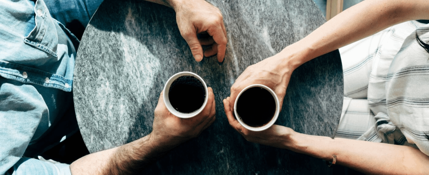 Two men sitting at table with cups of coffee