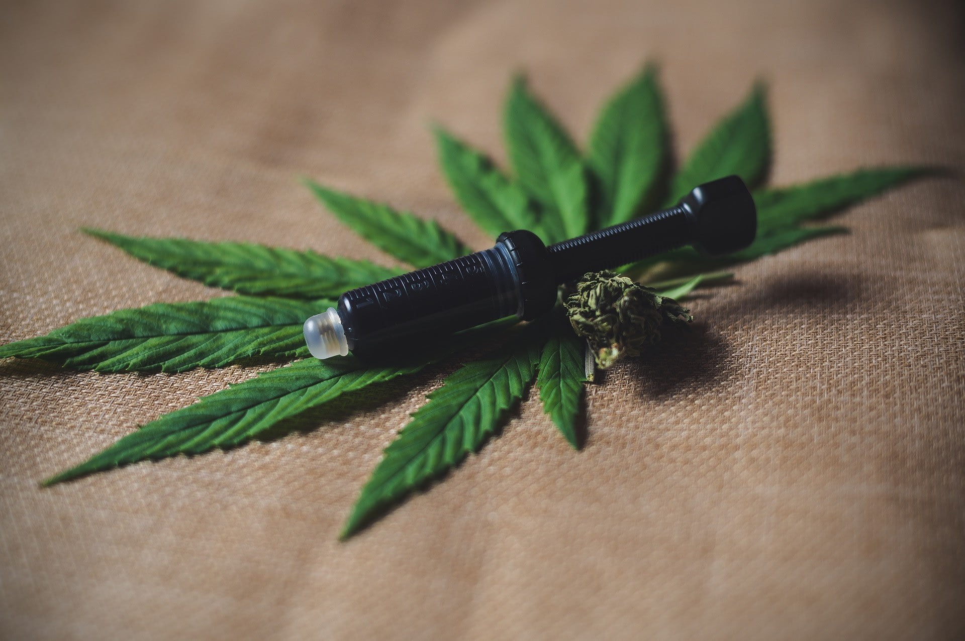 Vaporizer pen laying on top of marijuana leaf