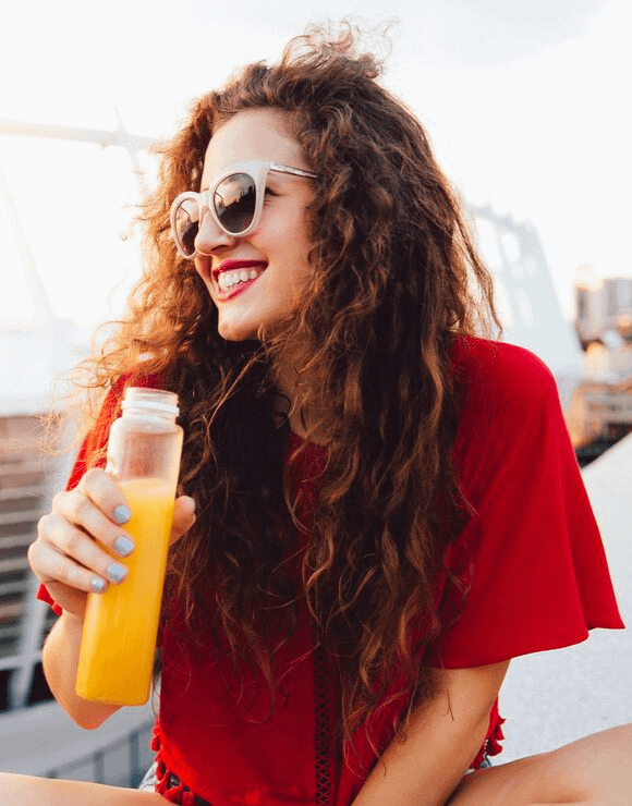 Happy brunette woman drinking juice