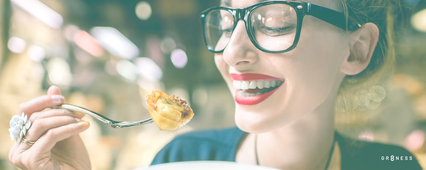 Woman wearing glasses eating a dumpling