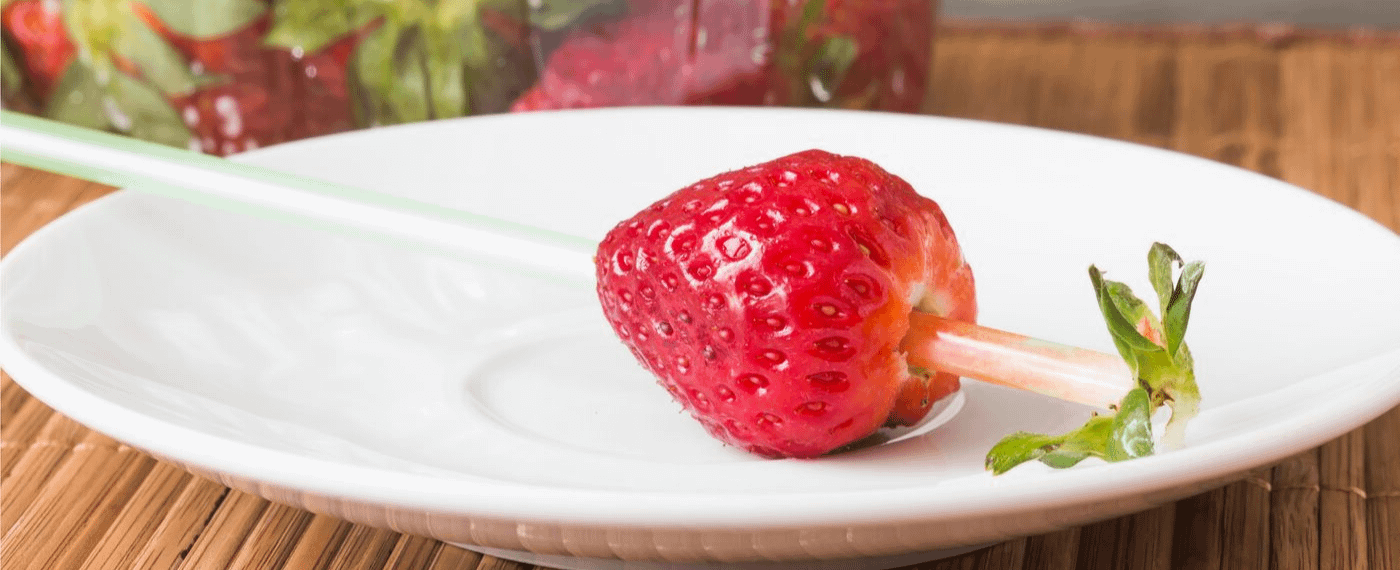 Straw piercing a strawberry to remove the green stem