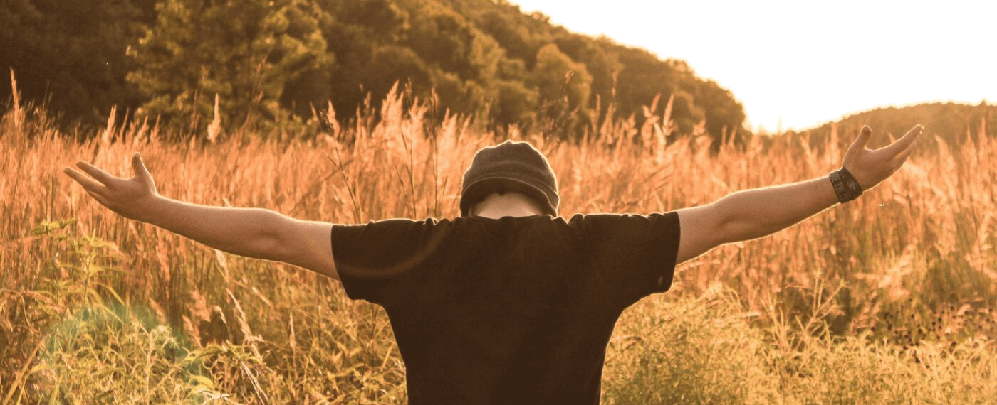 Man standing in a field with outstretched arms