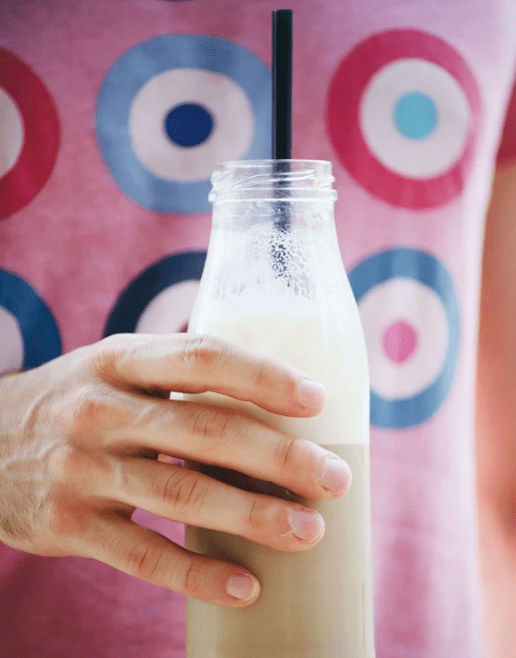 a glass jar of milk with a large straw sticking out