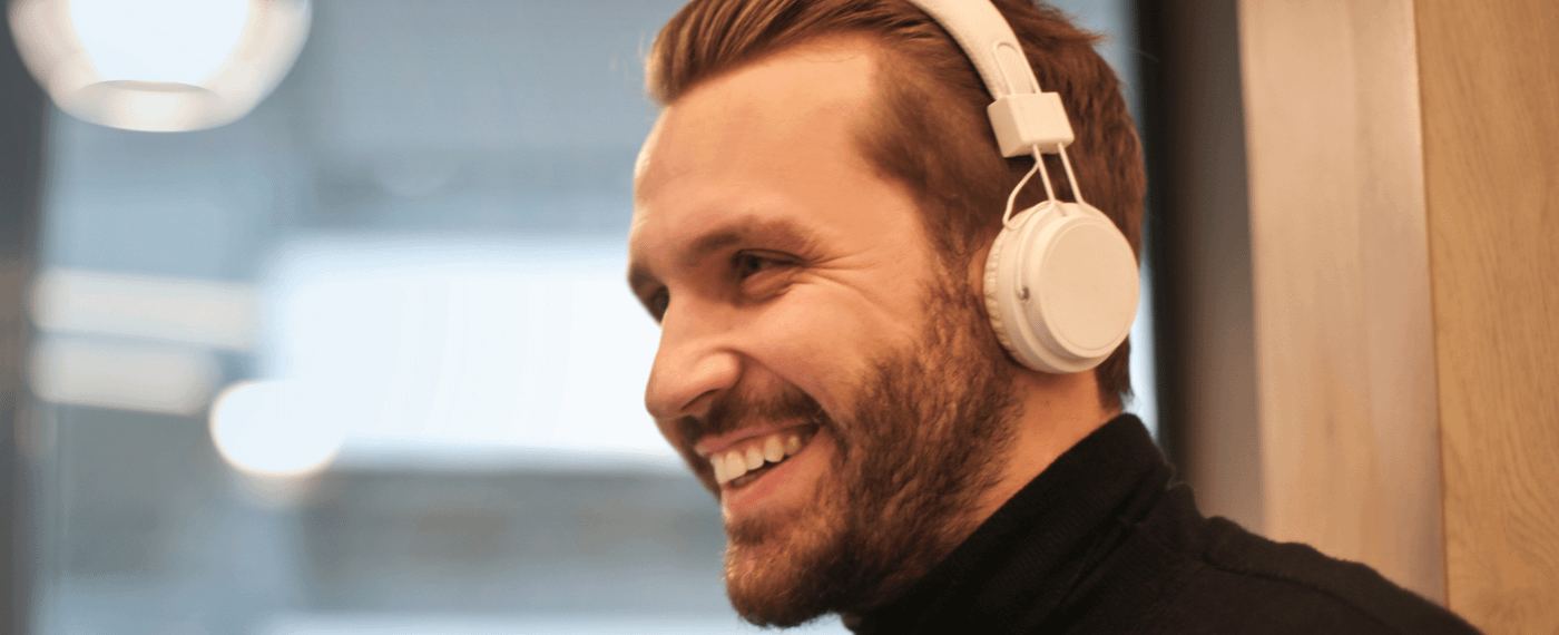 A smiling man with headphones listens to an effective self-care app