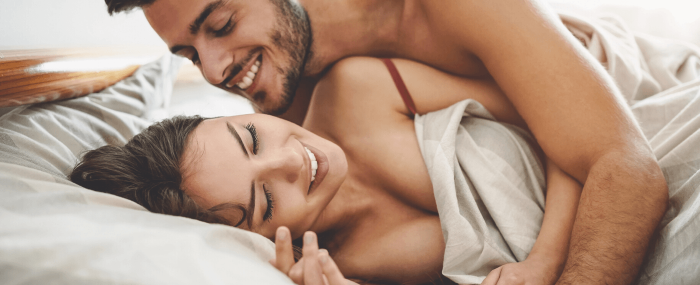 man and woman smiling in bed together