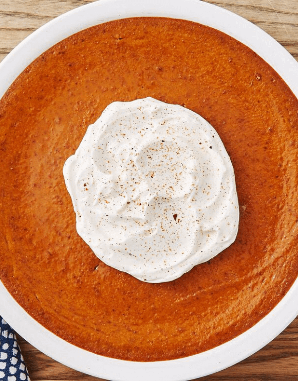 A round Crustless Pumpkin Pie with a whipped cream dollop in the center