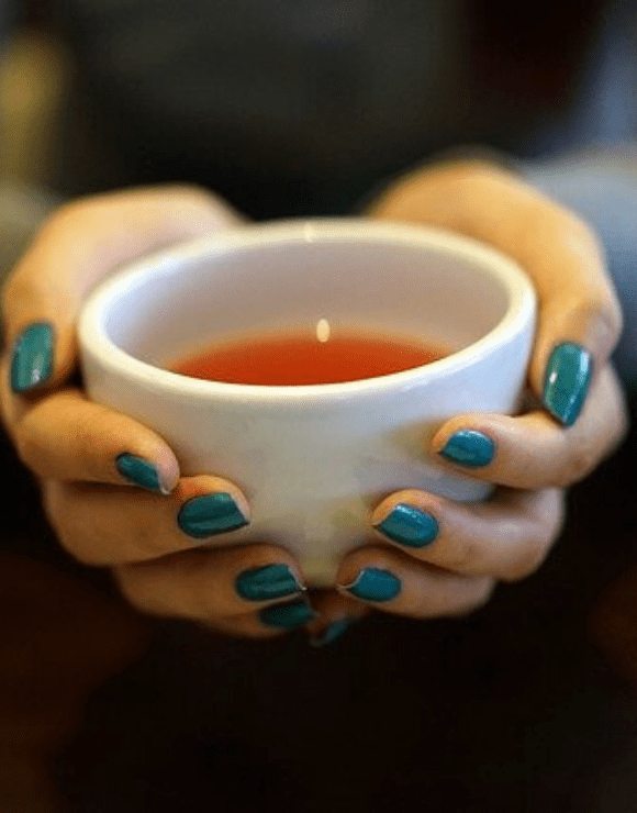 A cup of chamomile tea held in a woman's hands