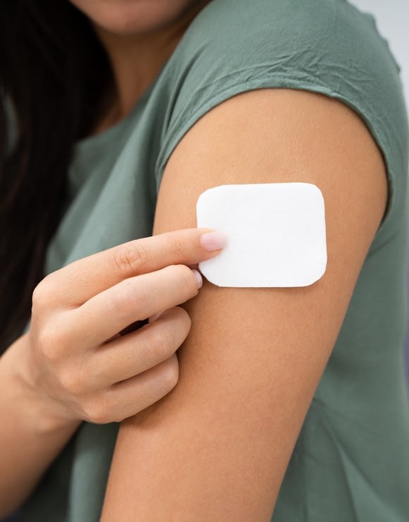 woman applying a birth control patch to the side of her arm