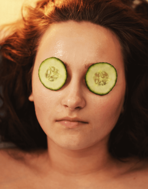 Woman relaxing with cucumber slices resting on her baggy eyes