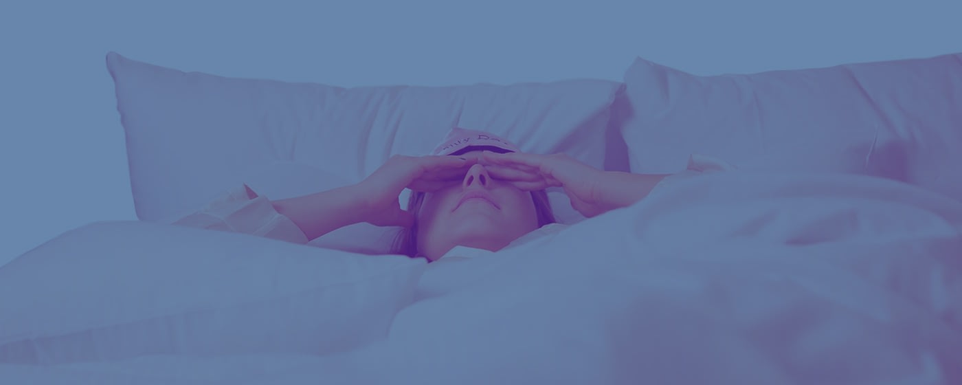 Woman rubs eyes after waking up from stressful sleep
