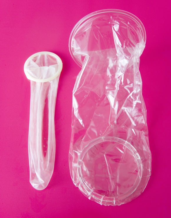 An internal condom lying next to a condom