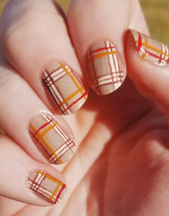Up close view of a woman's manicure using a plaid nail polish