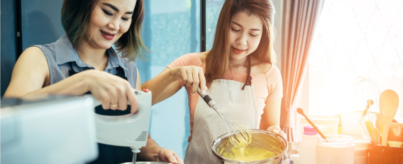 two sisters whisking cake batter together while baking