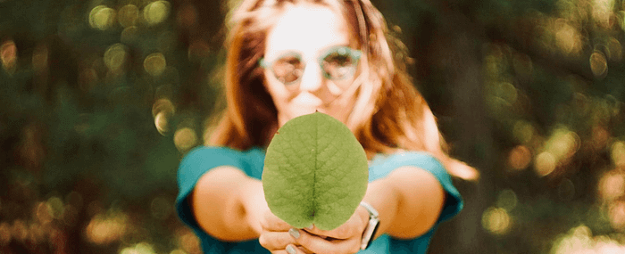 Girl wearing sunglasses in the sun holding a leaf