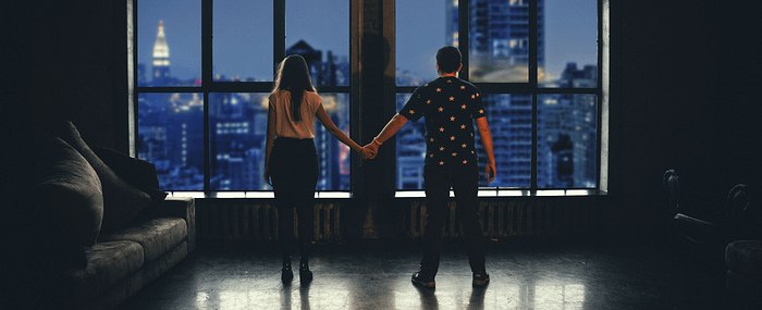 Woman and man holding hands overlooking city scape