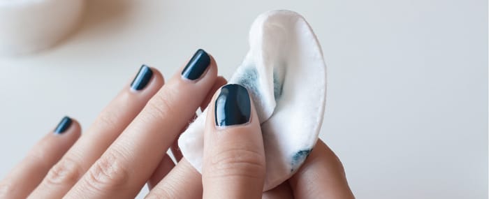 woman removing blue nail polish with acetone pads