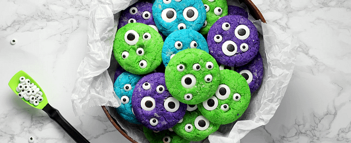 spooky halloween cookies in blue, green, and purple with googly eyes