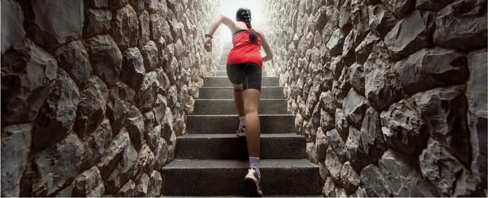 Woman in workout clothes running up stone steps