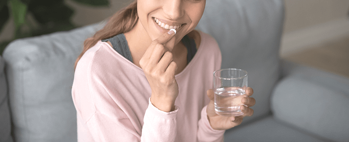 woman smiling while taking probiotic supplement