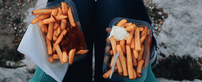two plastic containers of french fries with ketchup