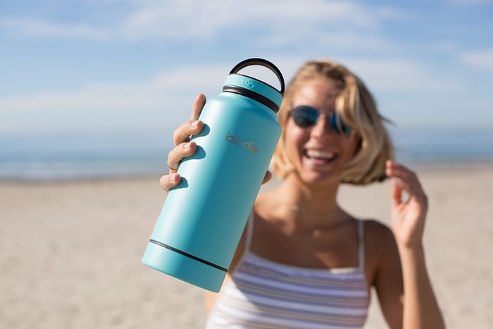 Woman smiles while holding up traveling water container