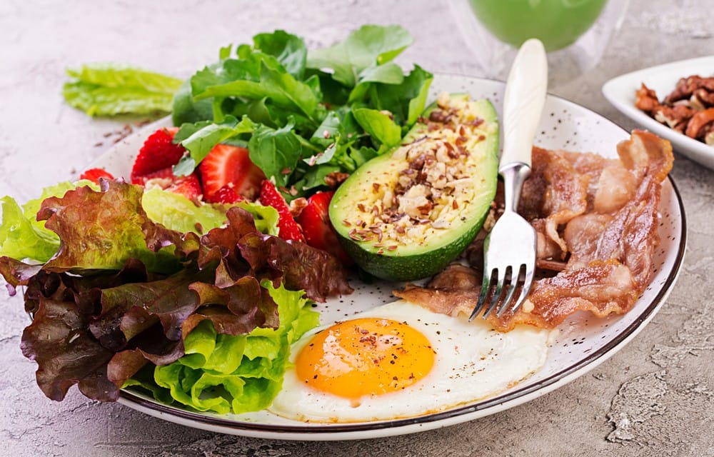 eggs with avocado and salad with strawberries on a plate as part of keto diet recipes