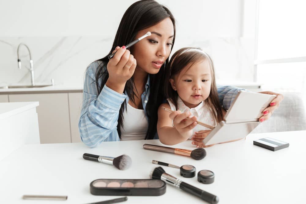 Mother introducing child to makeup by applying eyeshadow